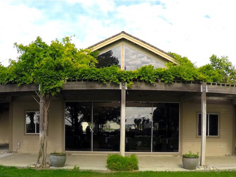 Exterior of a Ridgemark Golf Club & Resort event space with large windows and greenery-covered pergola.