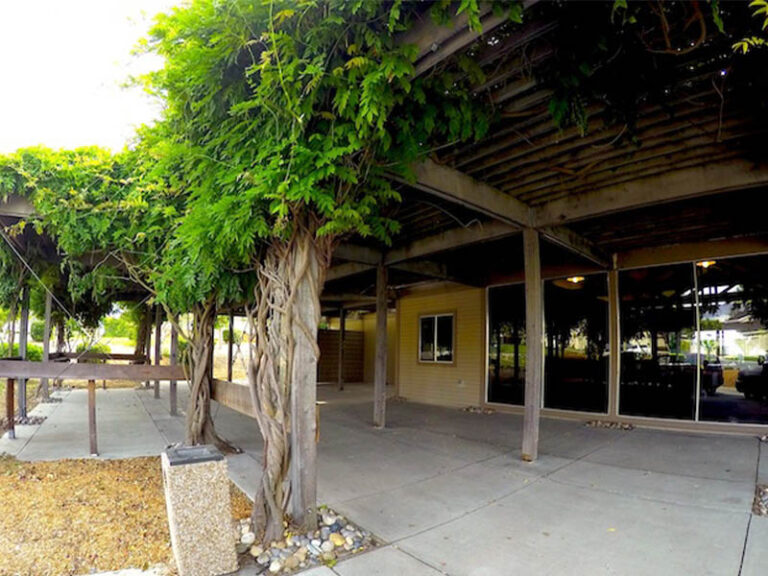 Covered patio outside the Ridgemark Golf Club & Resort event space with vines, walkways, and large windows.