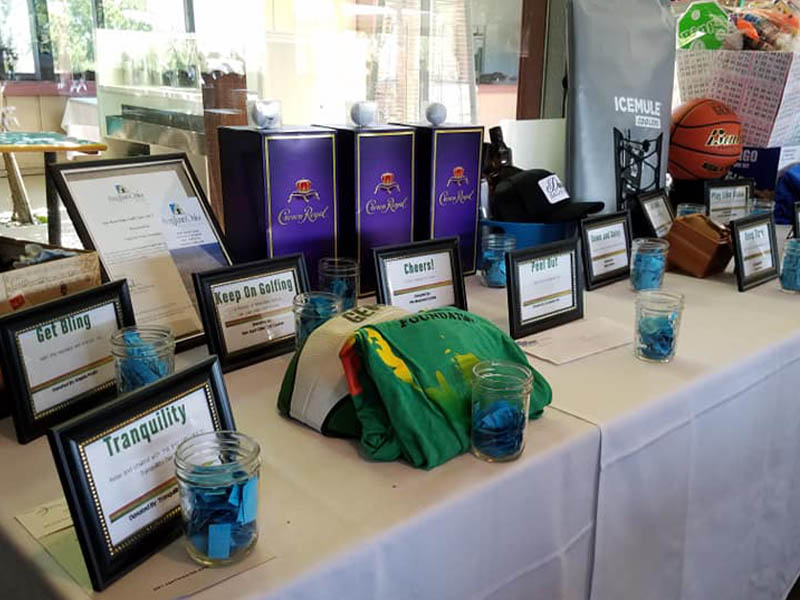 Silent auction table with framed bid signs, gift items, and golf-themed prizes for an event at Ridgemark Golf Club & Resort.