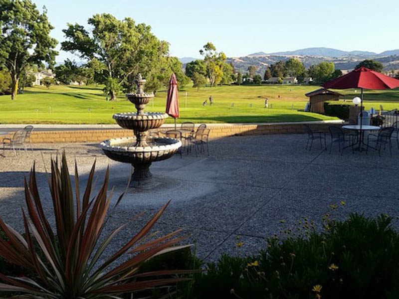Outdoor patio with fountain, seating, umbrellas, and golf course views at Ridgemark Golf Club & Resort.
