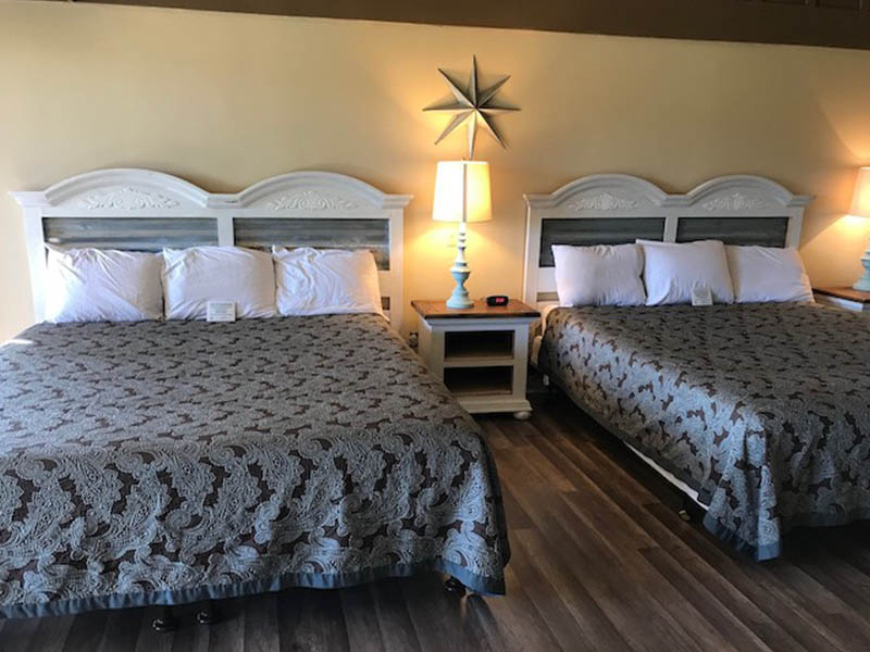 Guest room with two beds, white headboards, bedside lamps, and wood flooring at Ridgemark Golf Club & Resort.