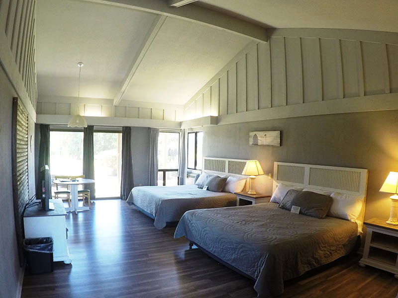Spacious Ridgemark Golf Club & Resort guest room with two beds, vaulted ceiling, table, and sliding glass door.