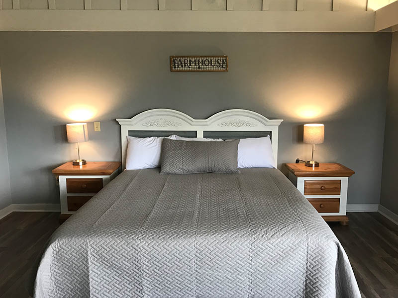 Guest room with a king bed, gray bedding, nightstands, and lamps at Ridgemark Golf Club & Resort.