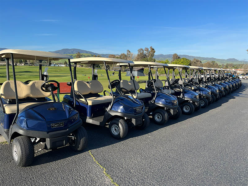 Row of golf carts lined up beside the practice area at Ridgemark Golf Club & Resort in Hollister, California, with green fairways and hills in the background.