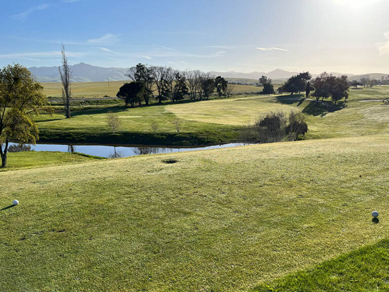 Tee box view of a Ridgemark Golf Club & Resort fairway with a pond and mountain backdrop.