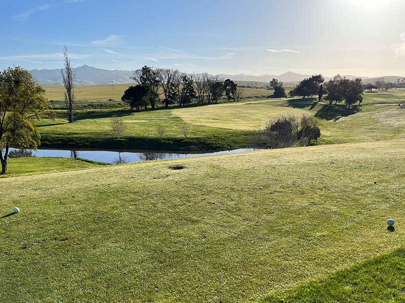 Tee box view of a Ridgemark Golf Club & Resort fairway with a pond and mountain backdrop.