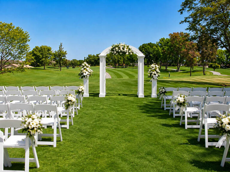 Outdoor wedding ceremony setup with white chairs, floral arrangements, and an arch overlooking the golf course.