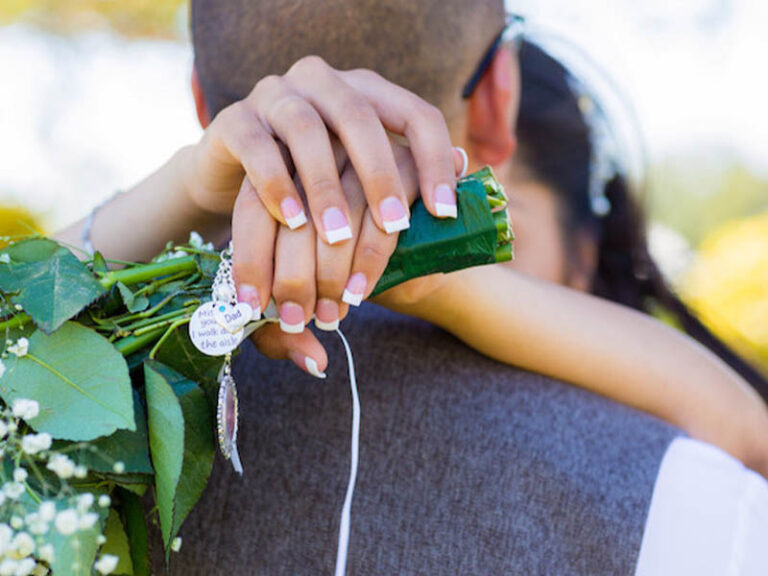 Bride holding a bouquet while embracing the groom during wedding portraits at the golf course.