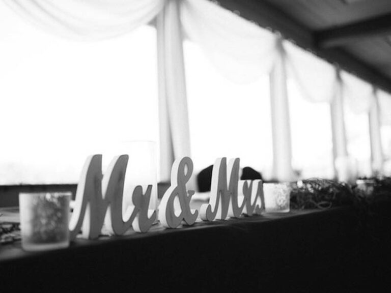 Black-and-white wedding reception detail with Mr. and Mrs. letters displayed near a window.